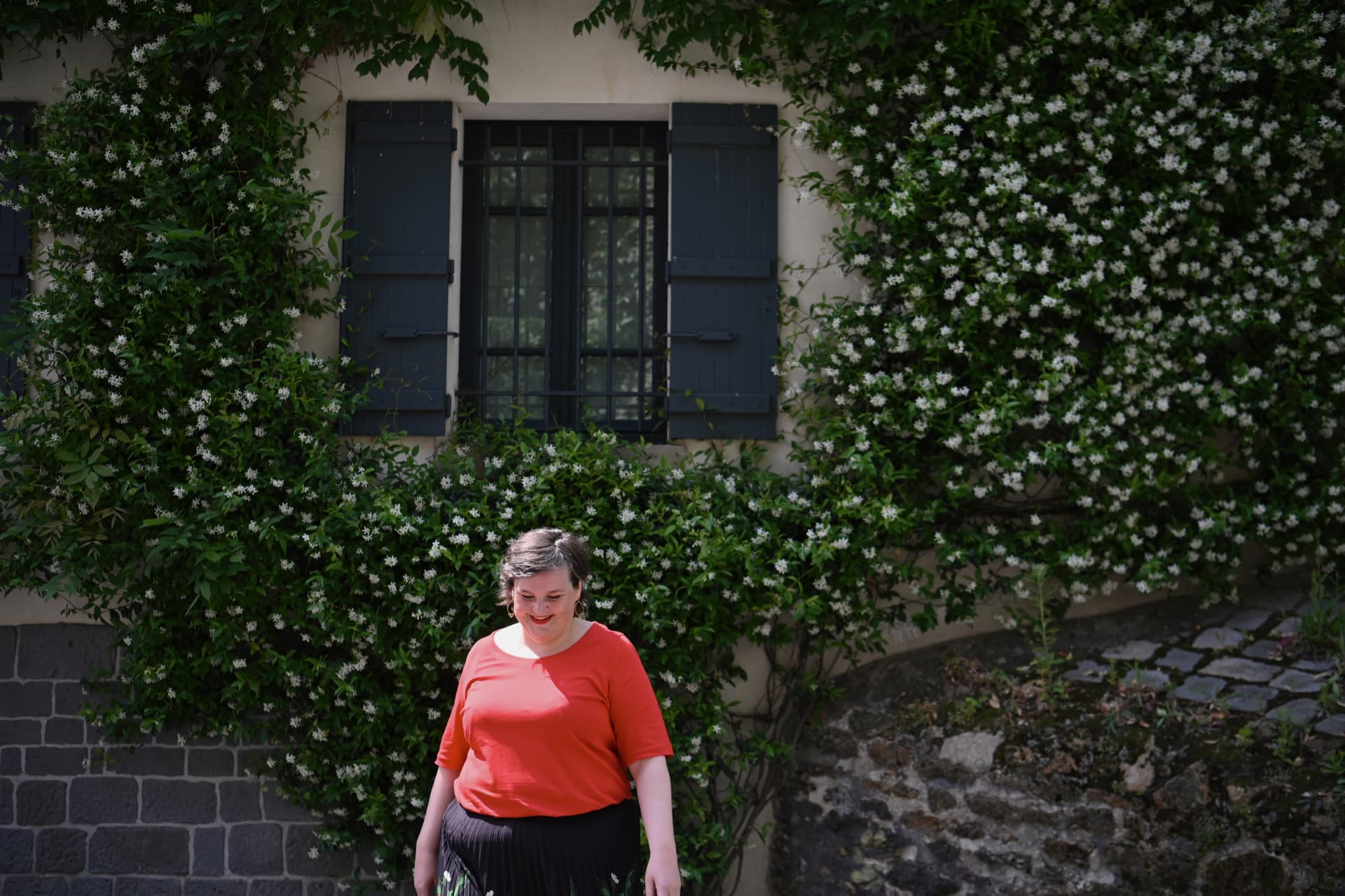 Sanne Frandsen standing in front of a flower-covered house