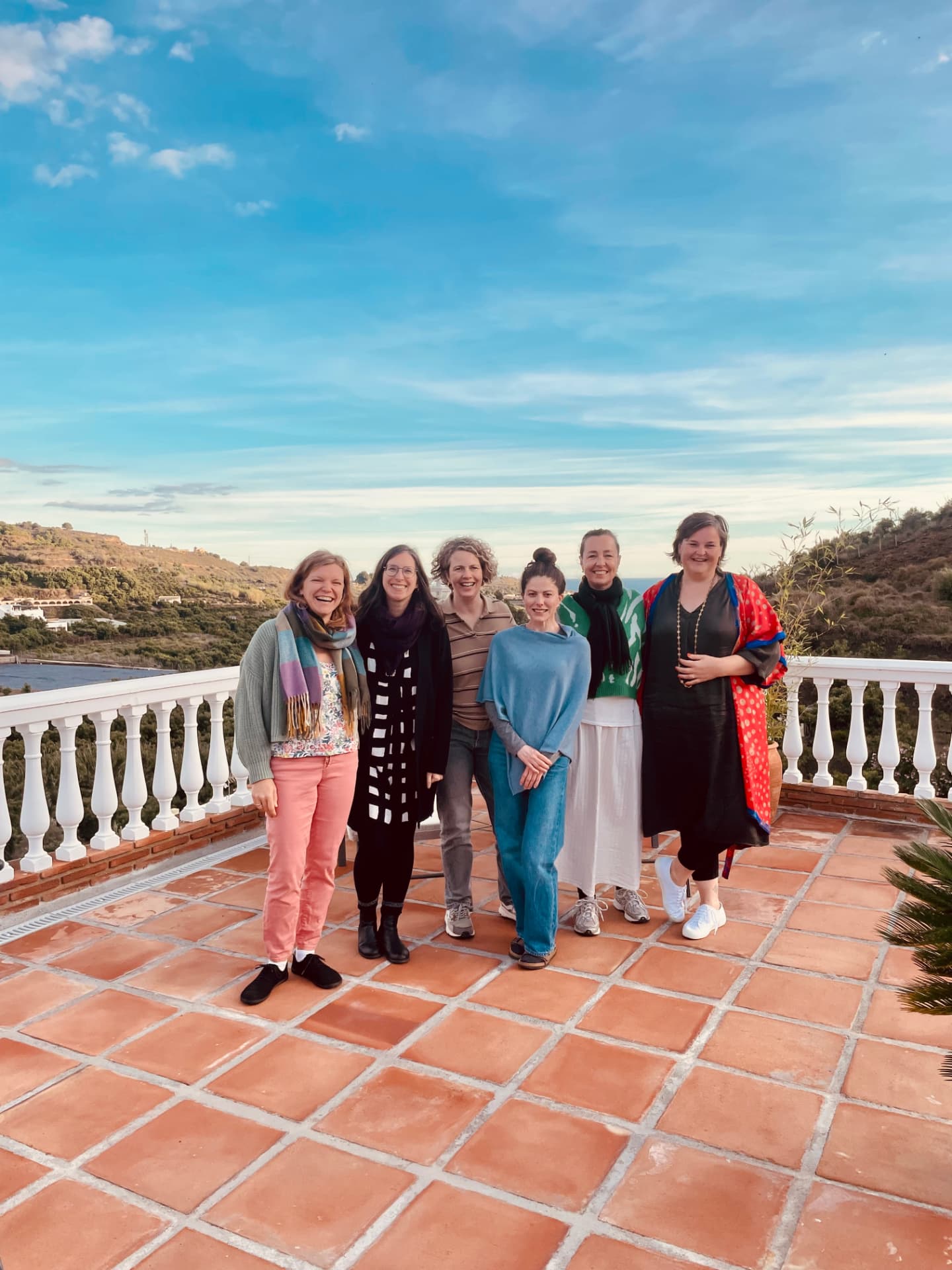 A small group of women academics standing together on a sunny terrace in the Spanish hills
